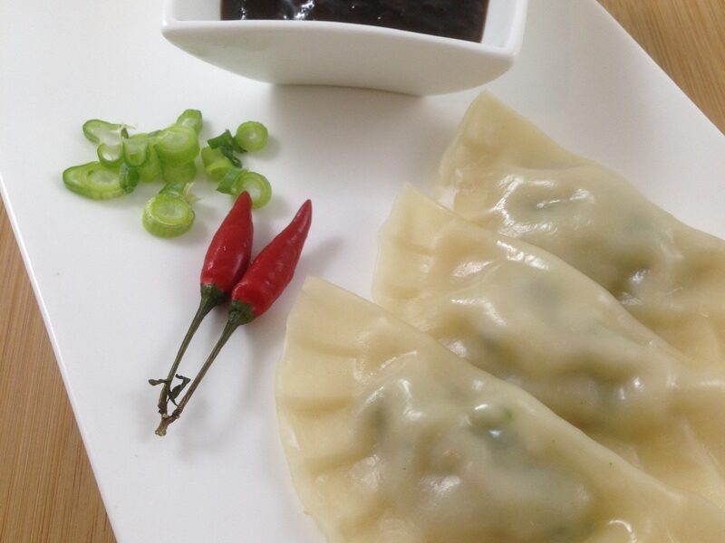 Thermomix Steamed pork dumplings on a plate with chilli sauce